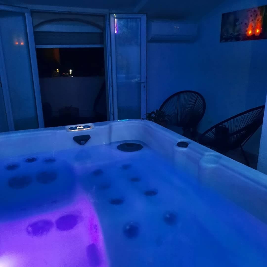 Jacuzzi avec reflets bleus et roses dans une atmosphère nocturne